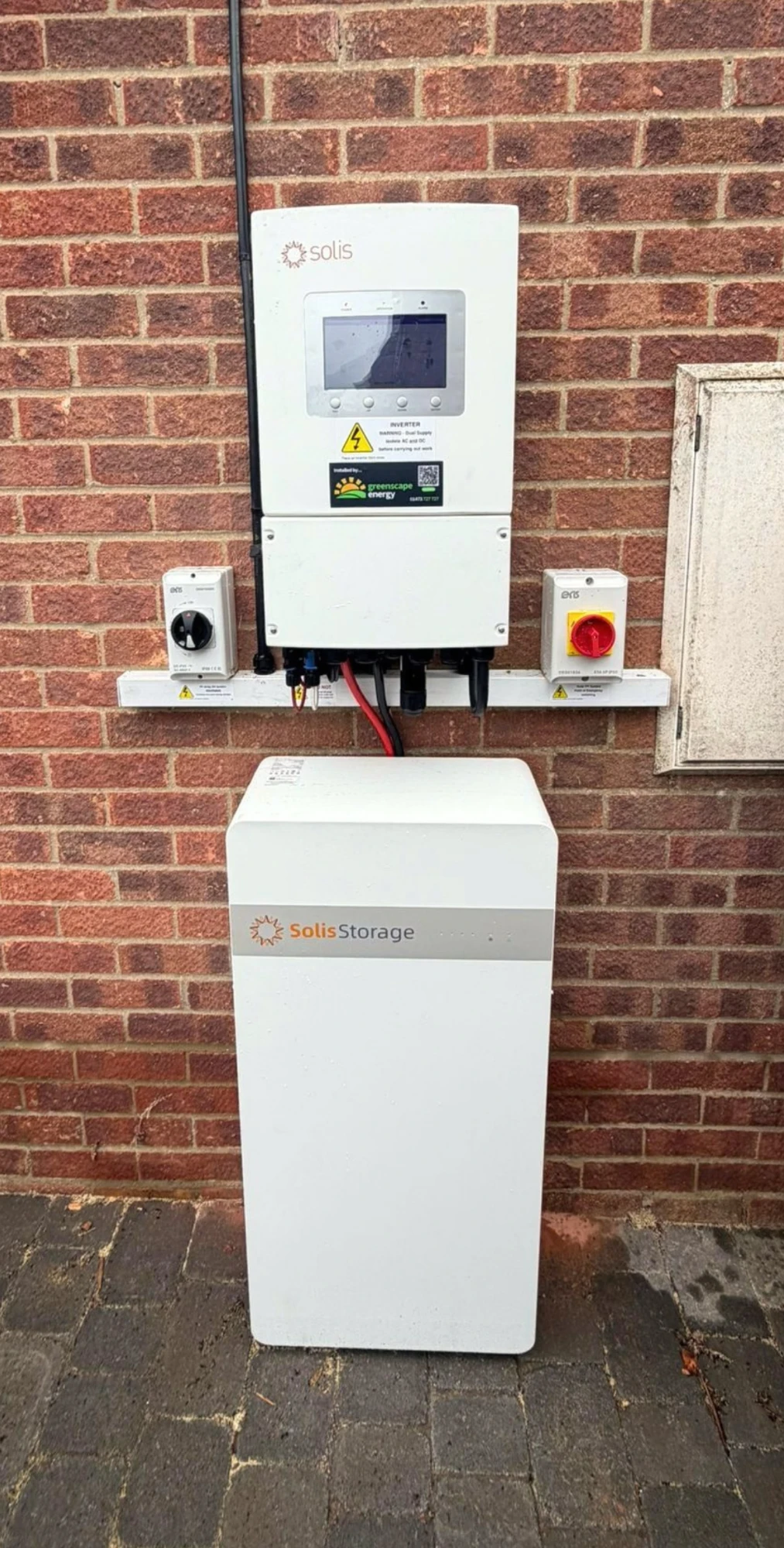 A Solis inverter and Solis Storage battery installed on a red brick wall