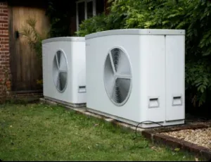 Two air source heat pumps side by side outside a house