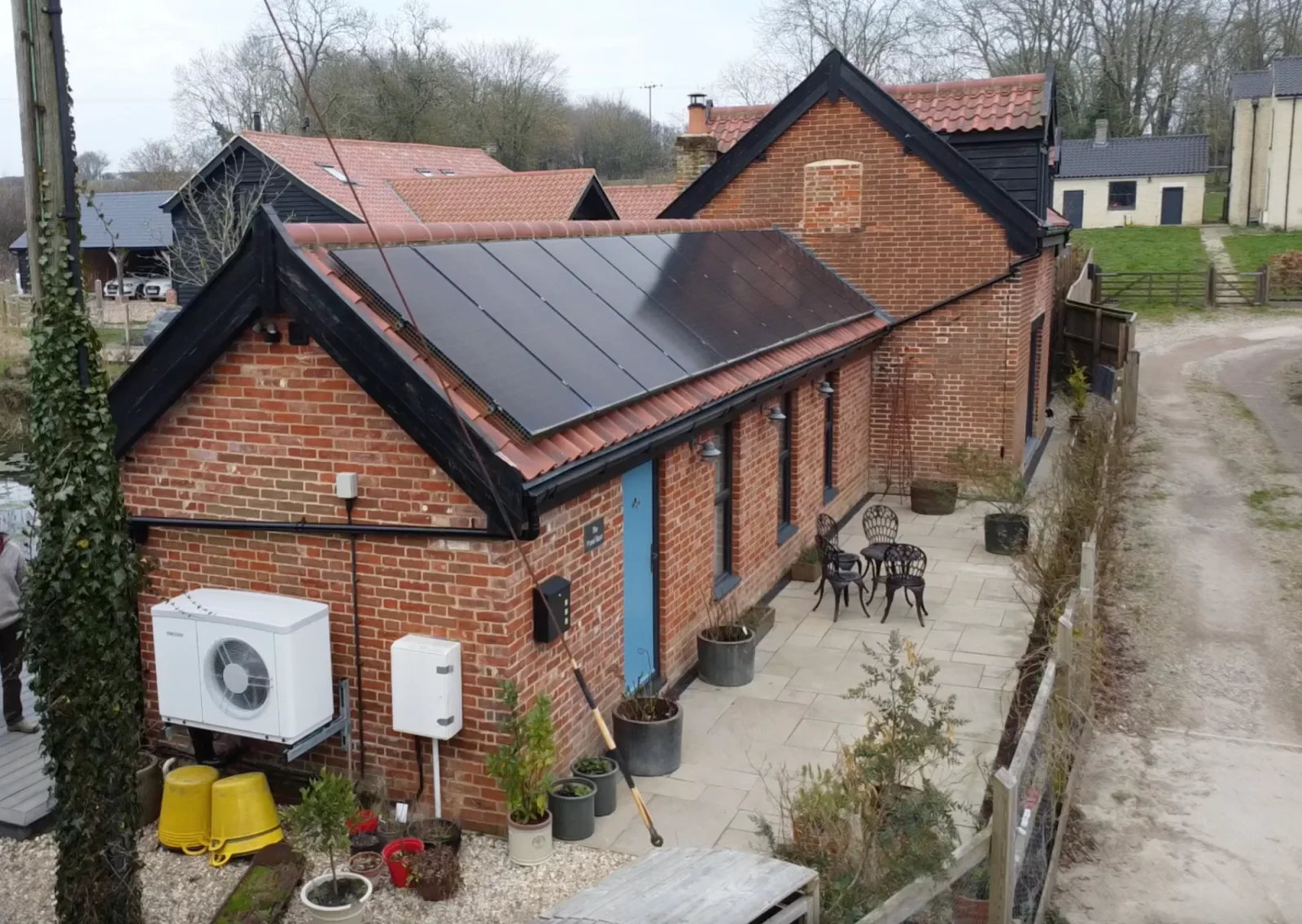Aerial view of Nick's brick barn conversion with black solar panels on the roof and an air source heat pump on the wall