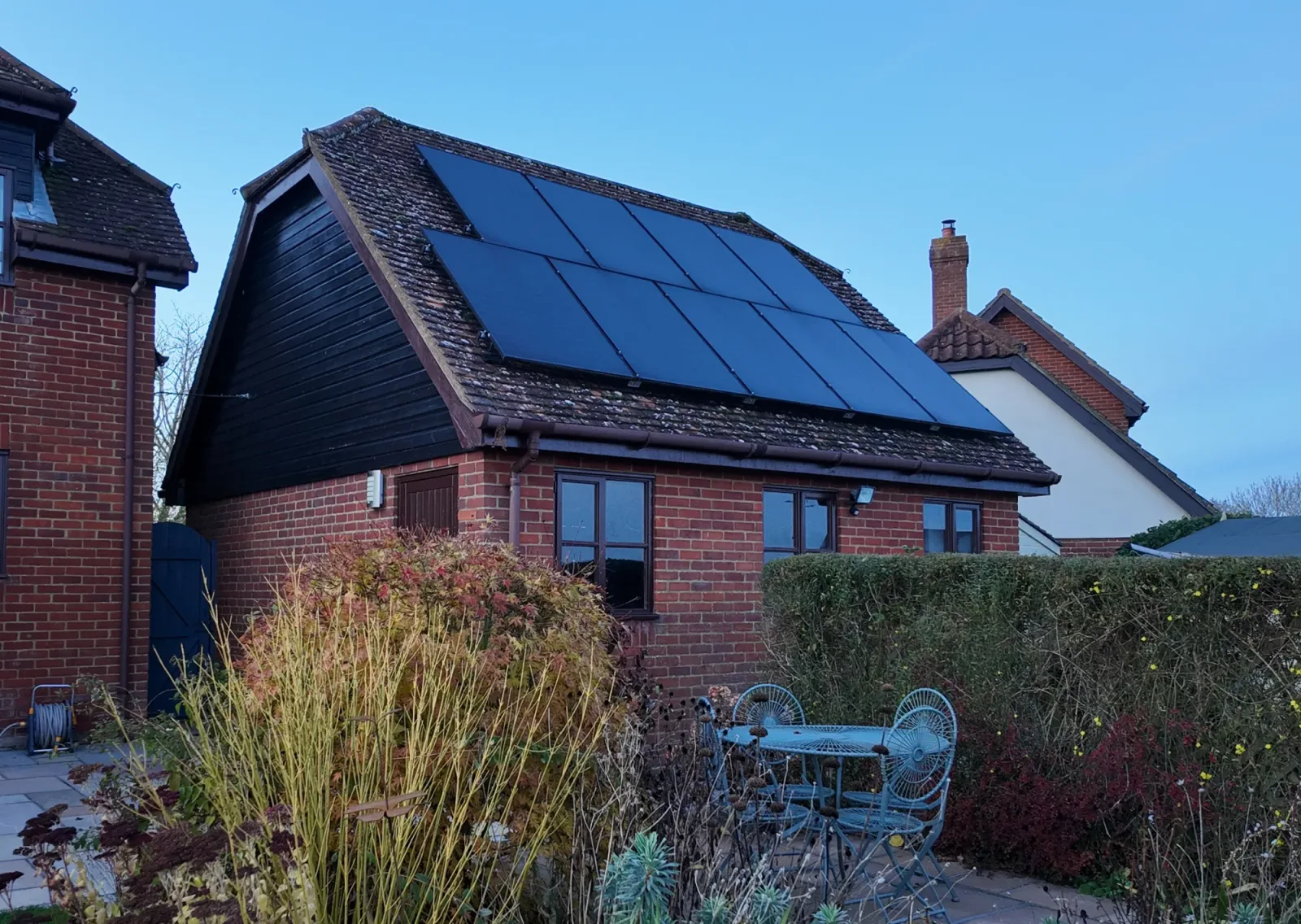 Richard's red brick outbuilding with black solar panels on its tiled roof under a blue sky