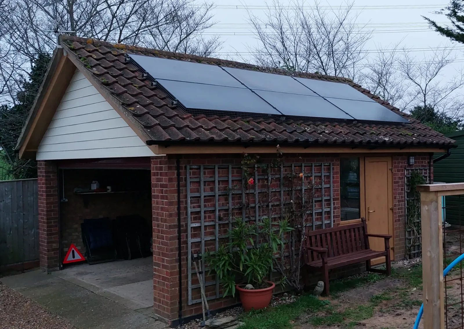 Ann's garage with six black solar panels on its tiled roof