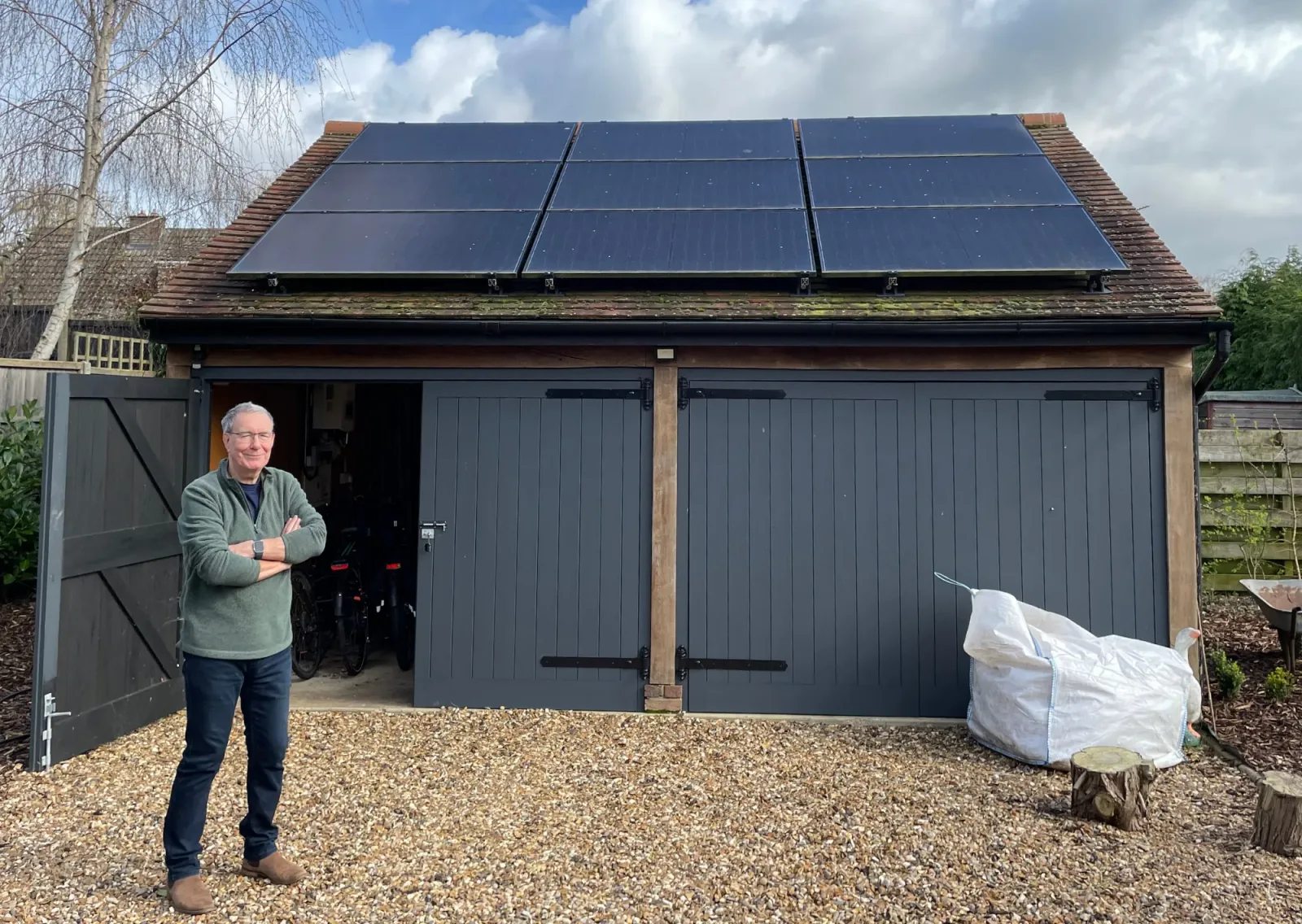 Phil outside his oak-framed garage with nine solar panels on the roof