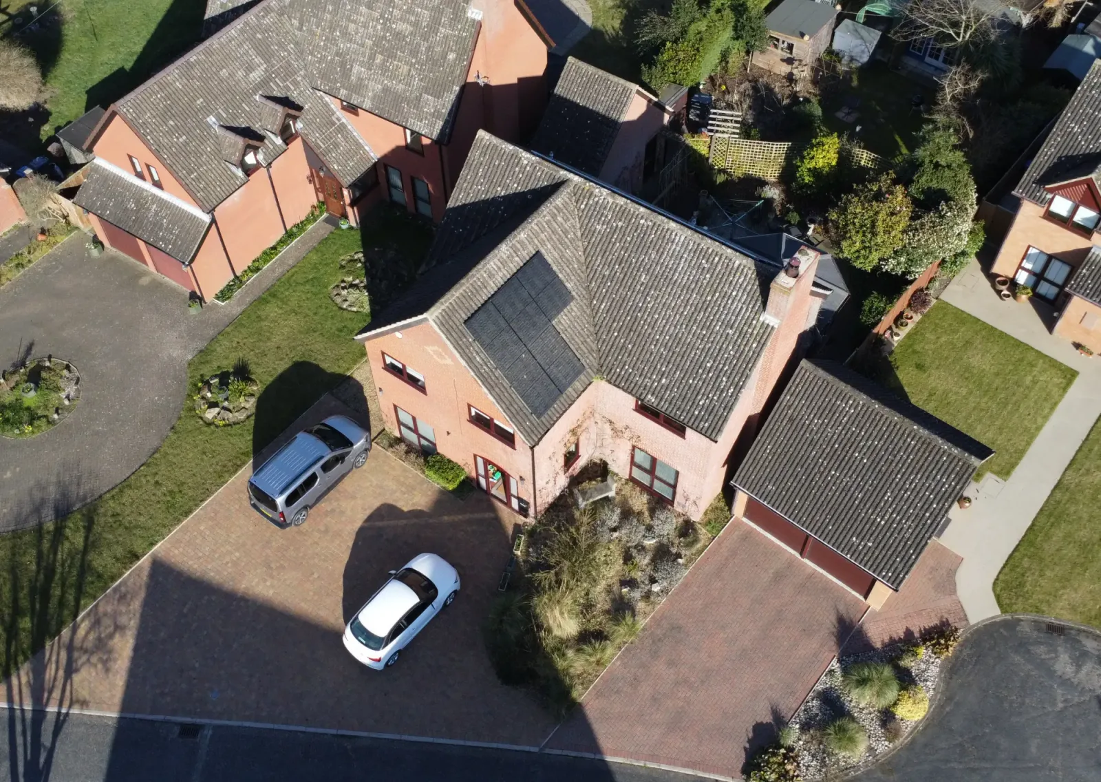 Aerial view of Caroline's brick house with black solar panels on the roof