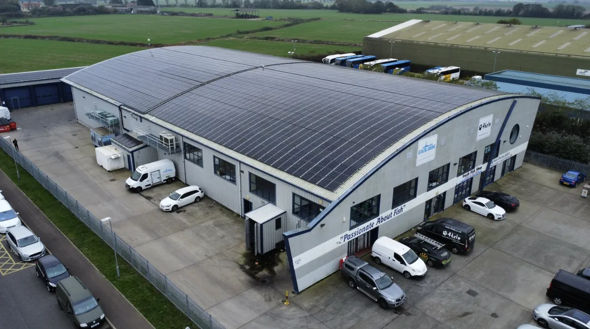 Aerial view of a commercial building with a long curved solar roof