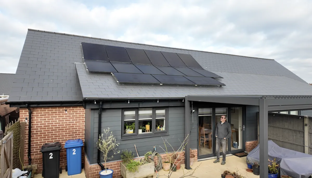 A single-storey home with solar panels, the owner standing at the door