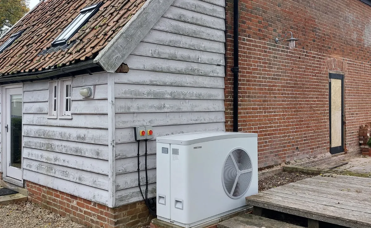 An air source heat pump outside a weatherboarded outbuilding