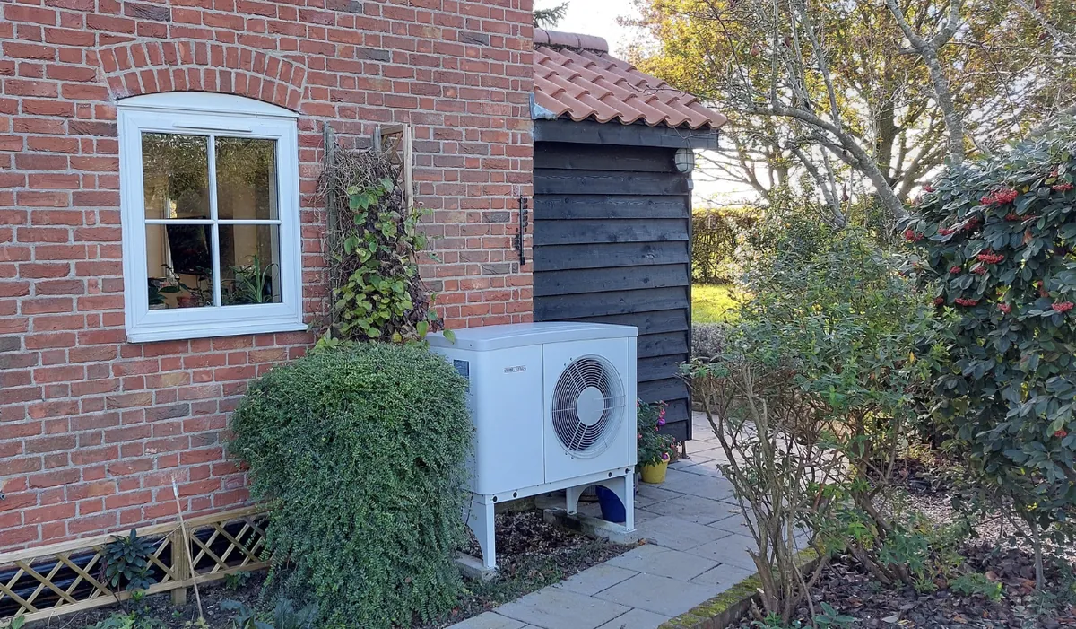 An air source heat pump beside a red brick house