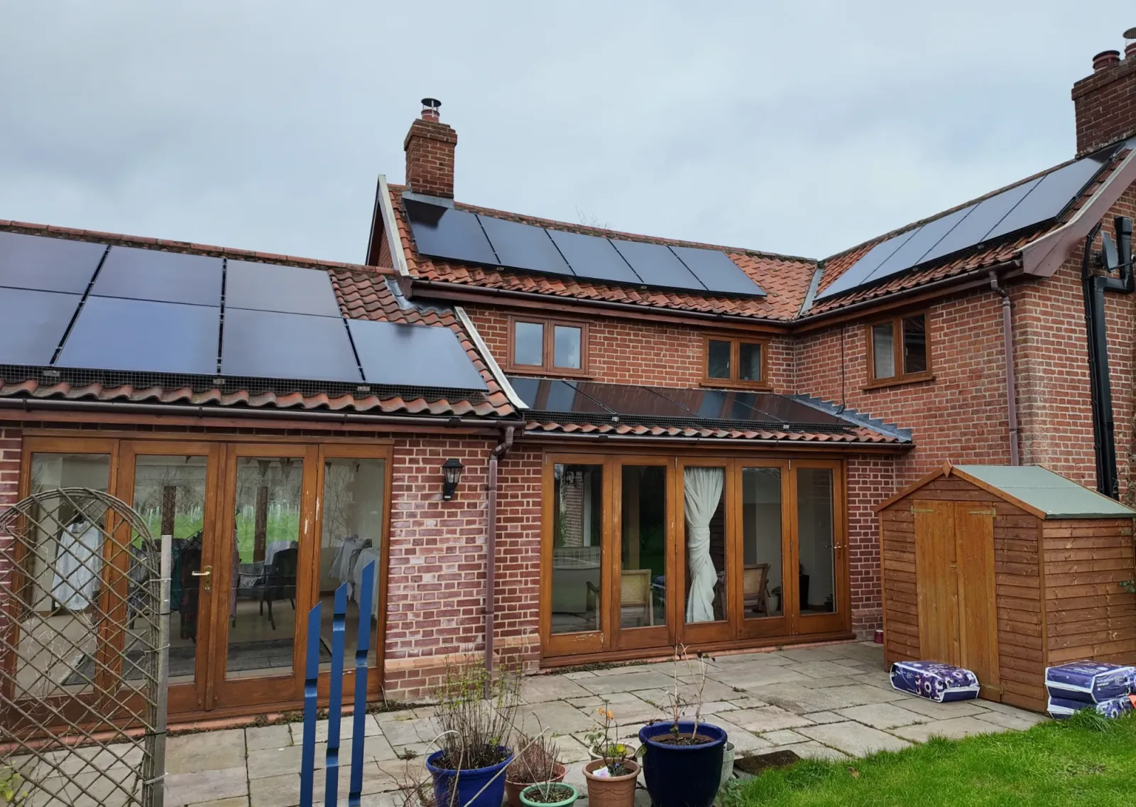 Shiv's brick country home with several arrays of black solar panels on its roofs