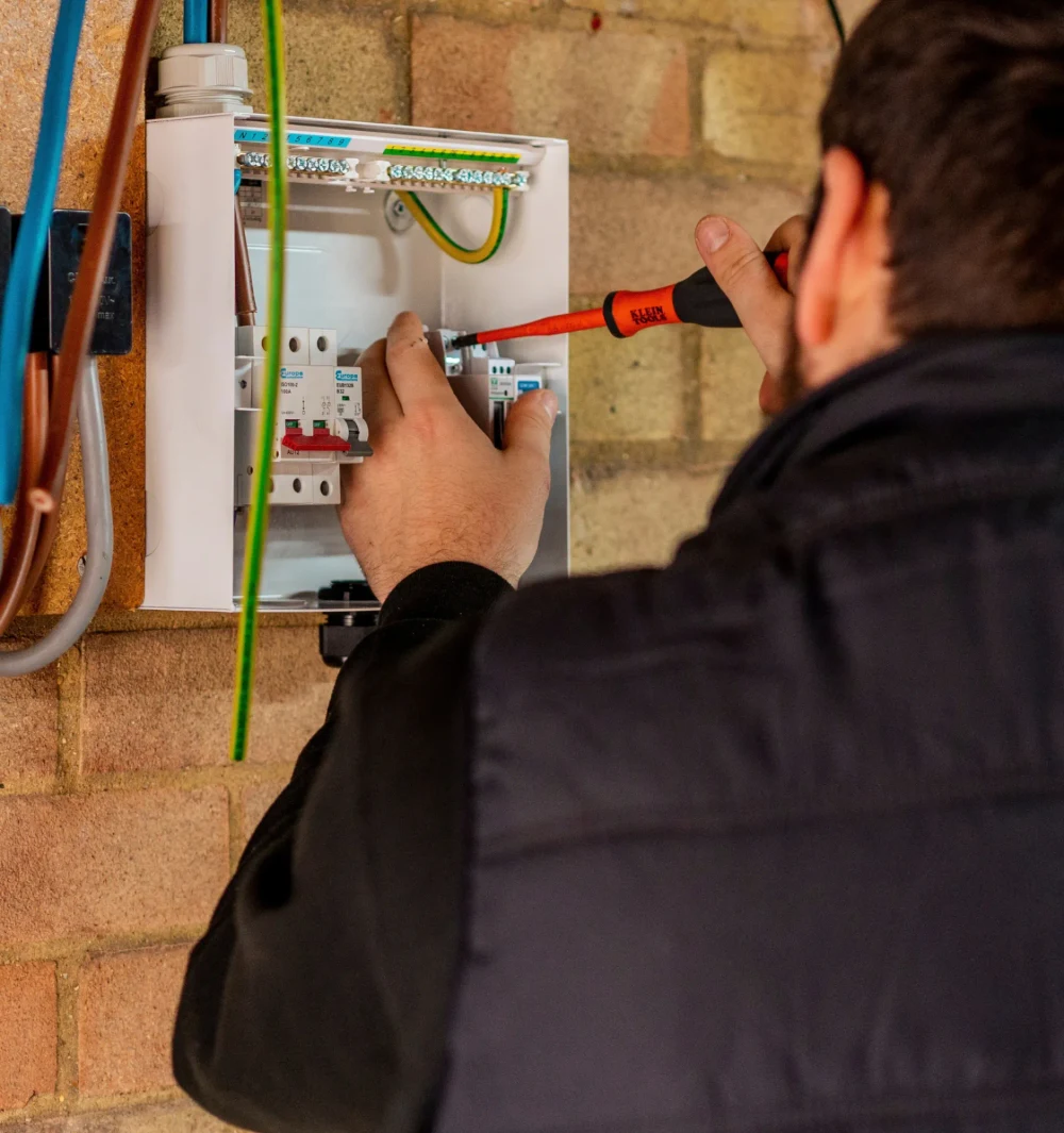 An electrician working inside a consumer unit
