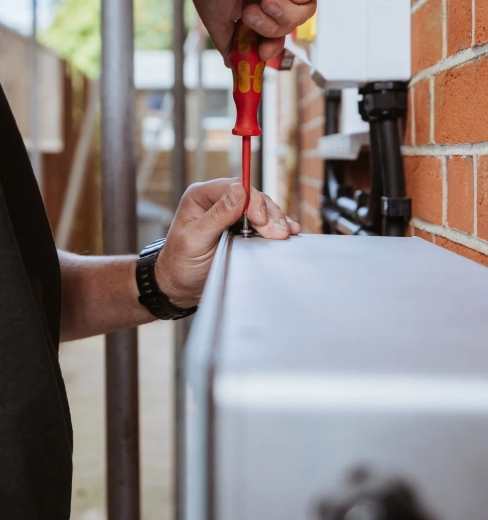 An installation engineer tightening a screw on a wall-mounted unit