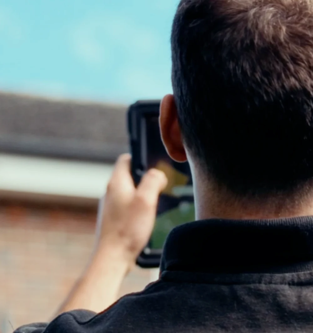 A Greenscape surveyor holding a tablet outside a house