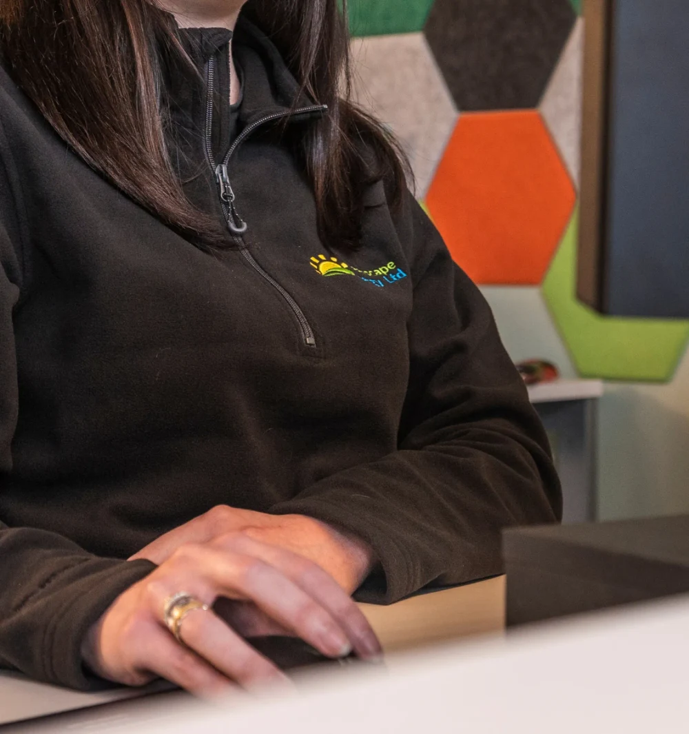 A member of the technical support team at a desk in a Greenscape fleece