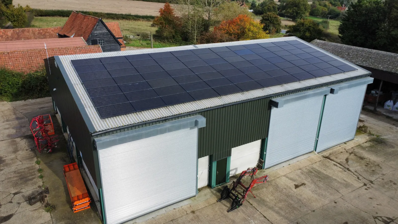 A farm building with roller doors and a roof of solar panels