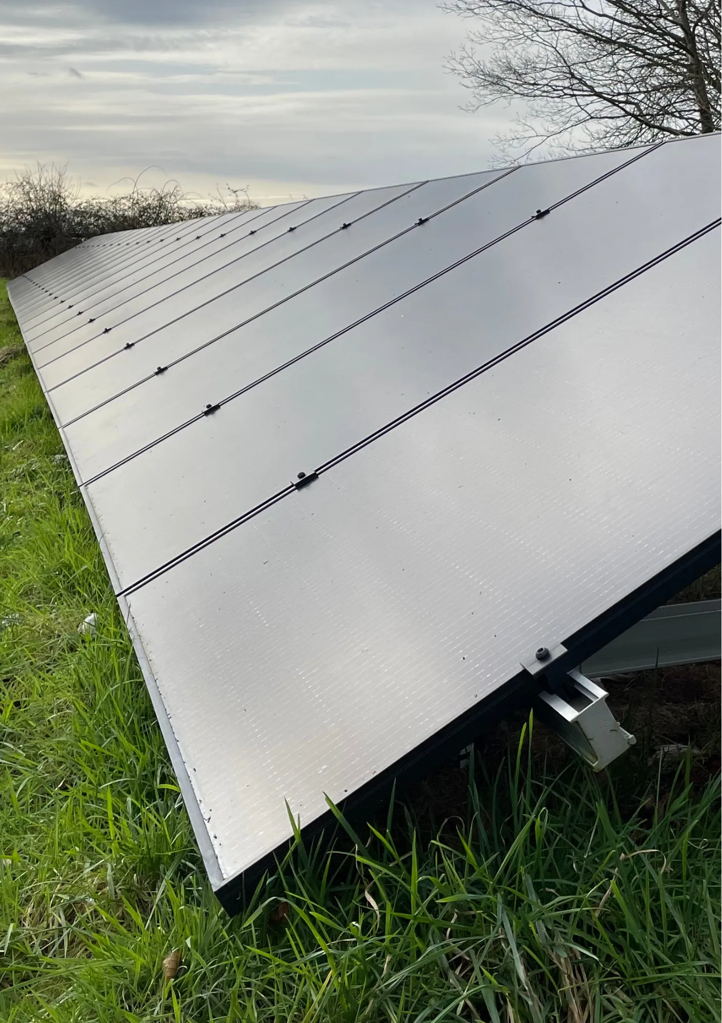 Rows of ground-mounted solar panels on grassland