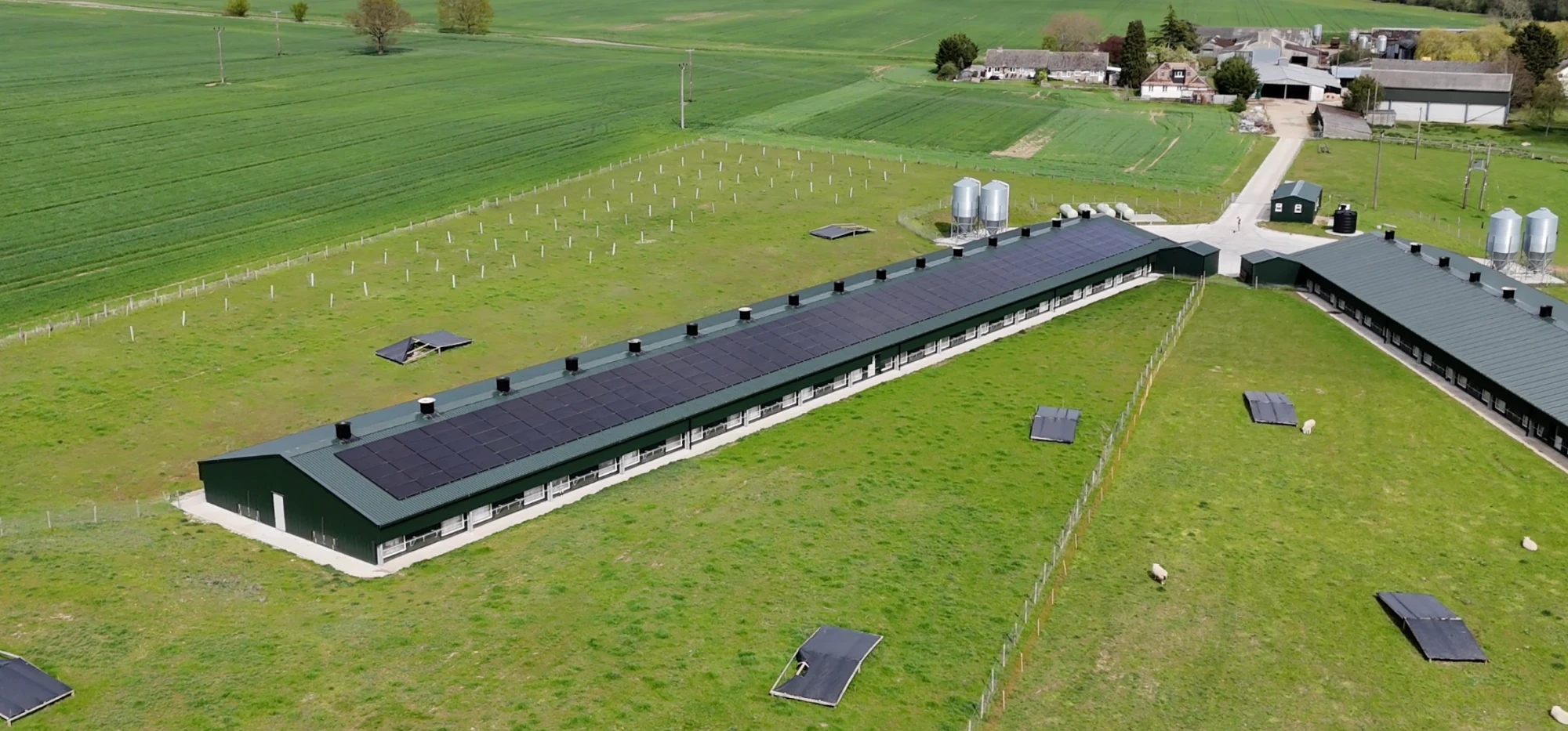 A farm shed with a solar roof, ringed by trees