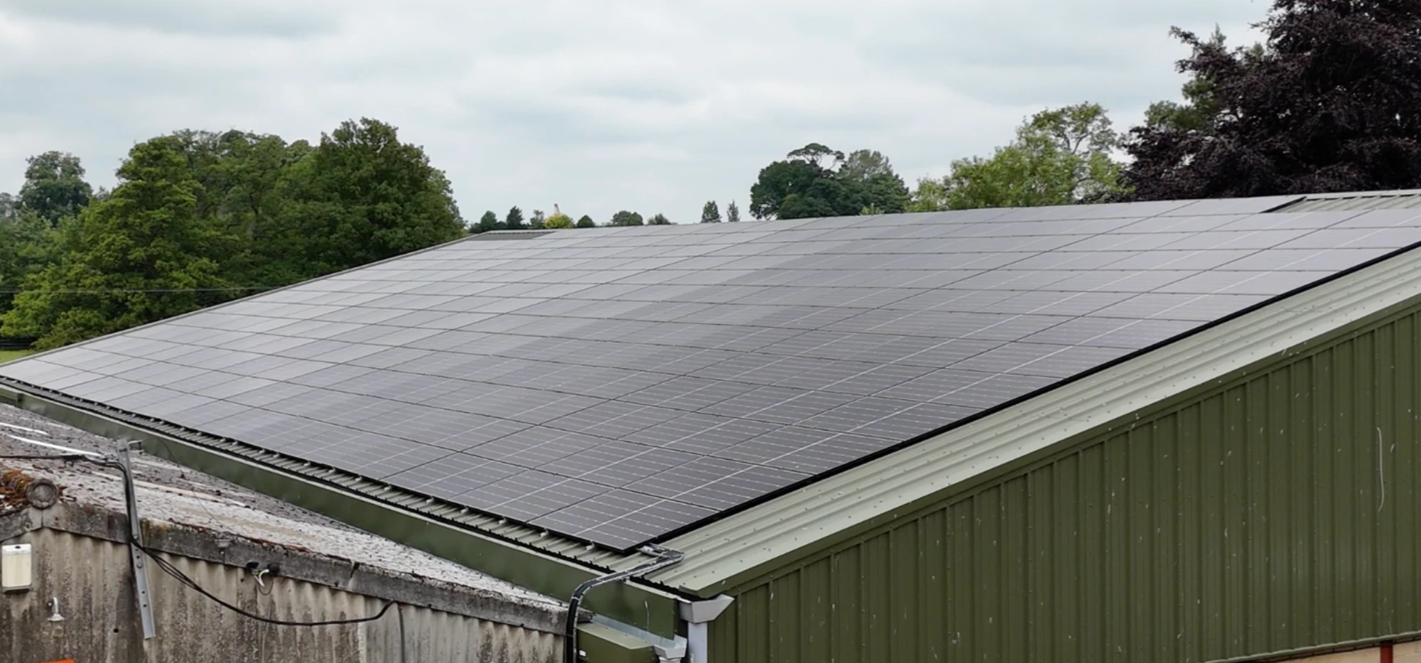 A farmyard seen from above, its main building roofed with solar panels