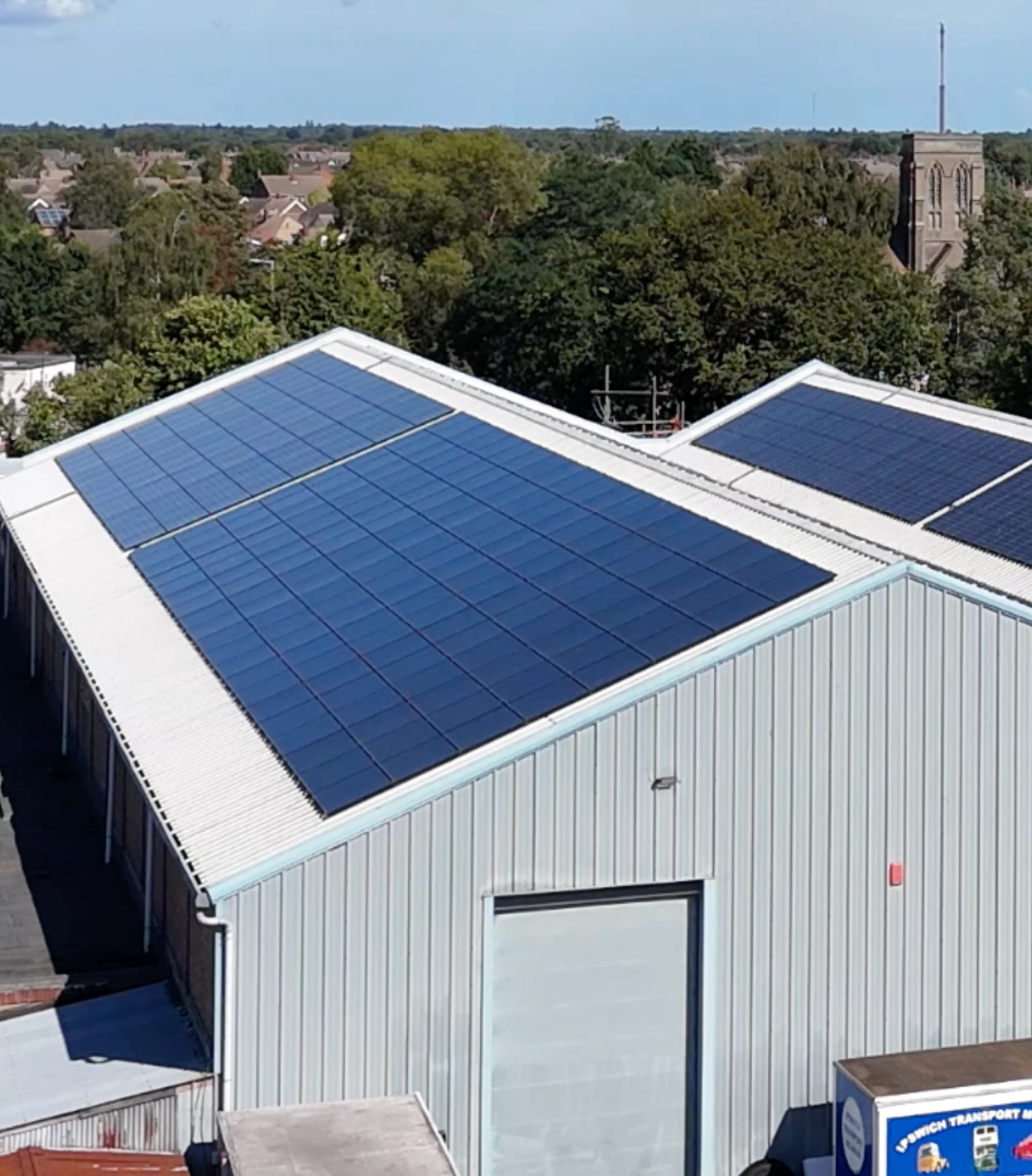 A commercial roof in a town, covered in solar panels