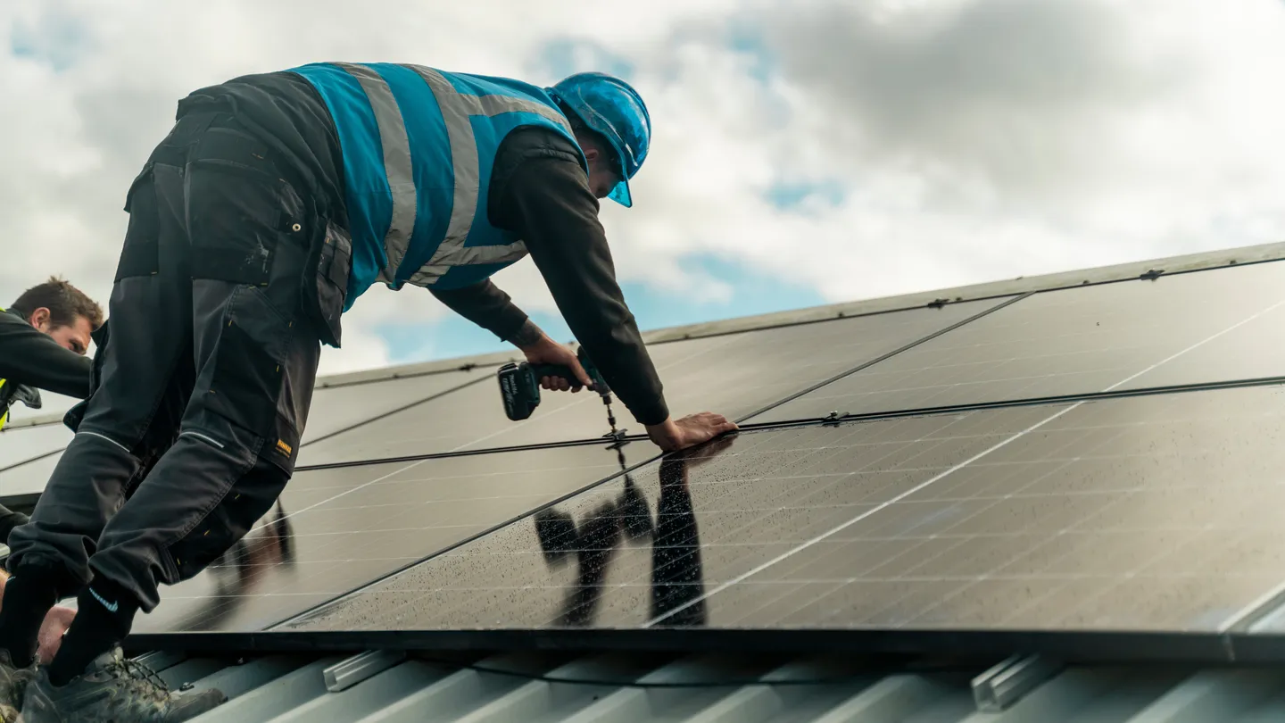 An installer in hi-vis fixing a panel to a roof