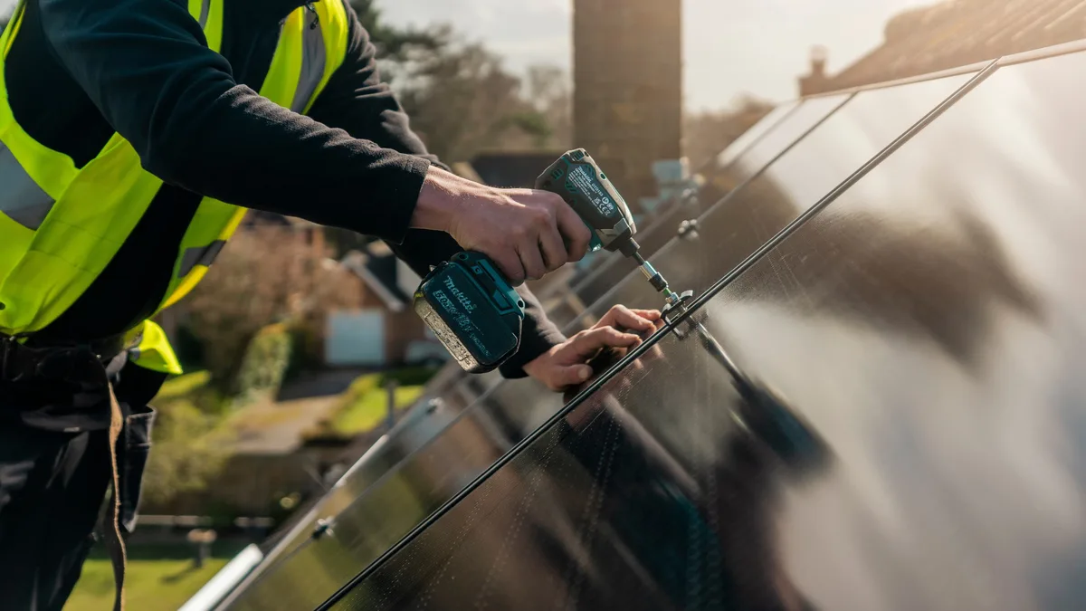 An installer fixing a solar panel to a roof rail