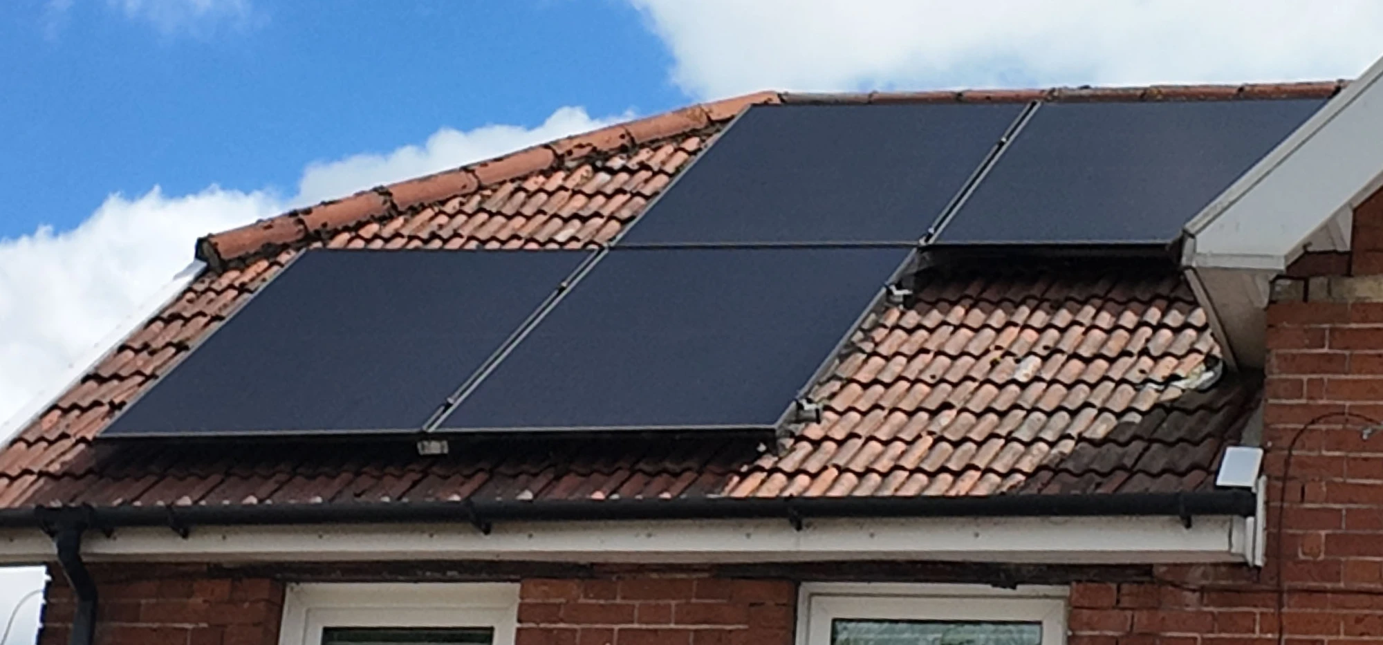 Solar panels on a red-tiled roof under a blue sky