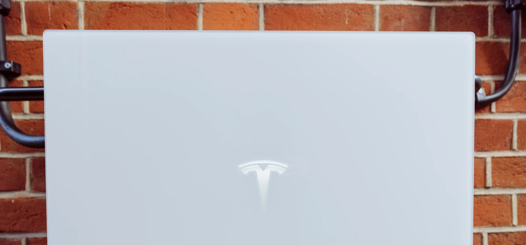 A home battery unit mounted on an exterior brick wall