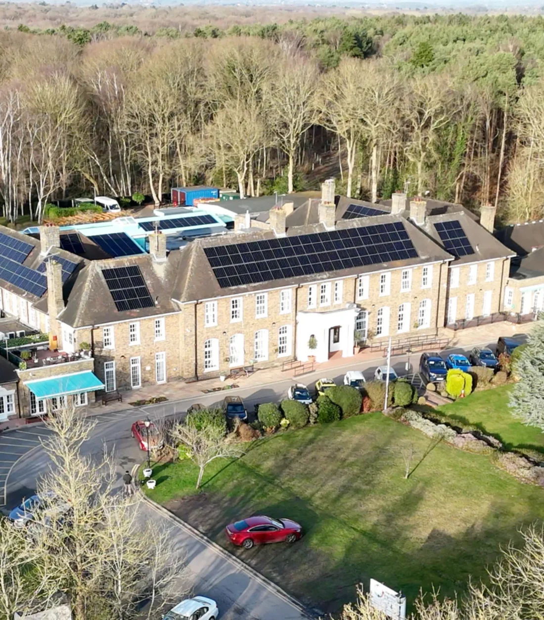 A country-house hotel with solar panels across its roofs, set in woodland